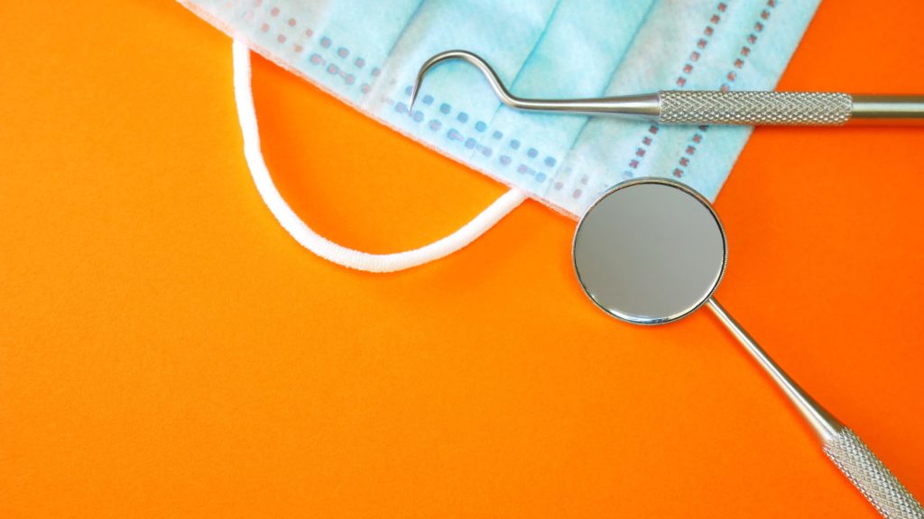 Dental tools and a mask on an orange background