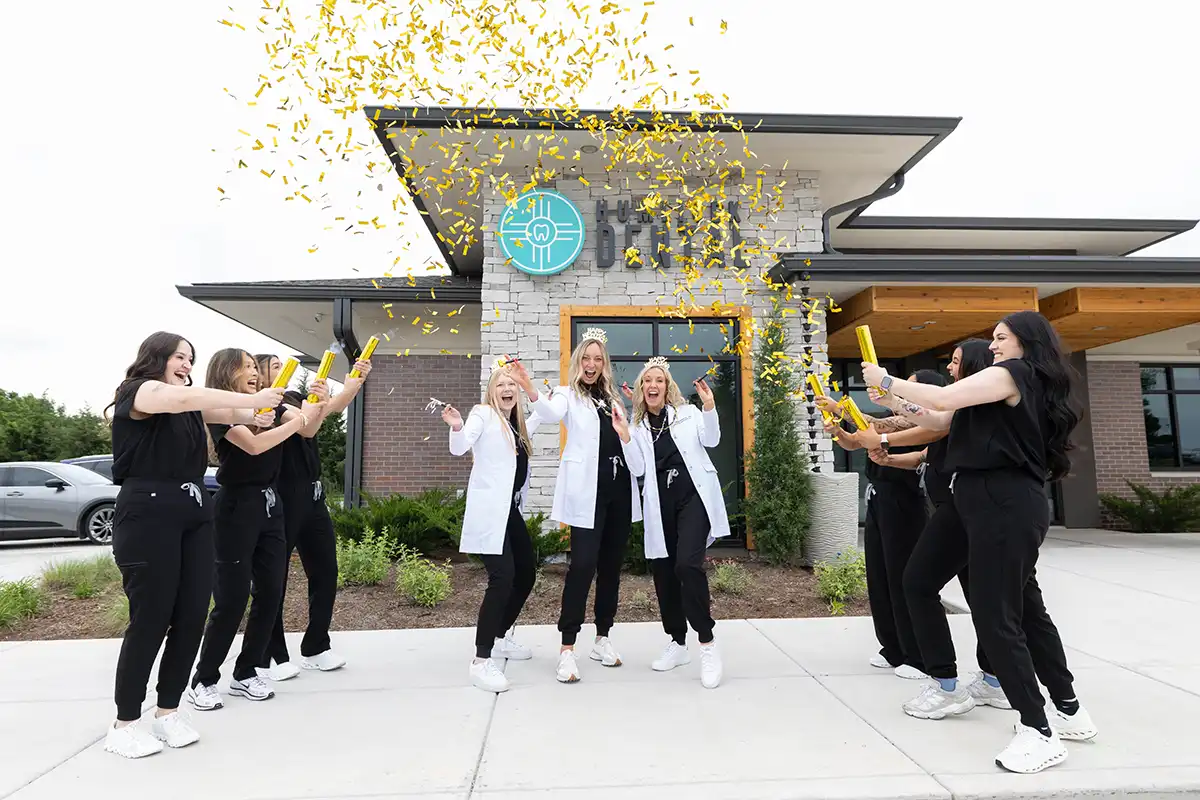 Humlicek Dental team celebrating outside the building with gold confetti.
