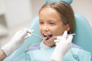 A young dental patient sits in an exam chair while getting a dental checkup