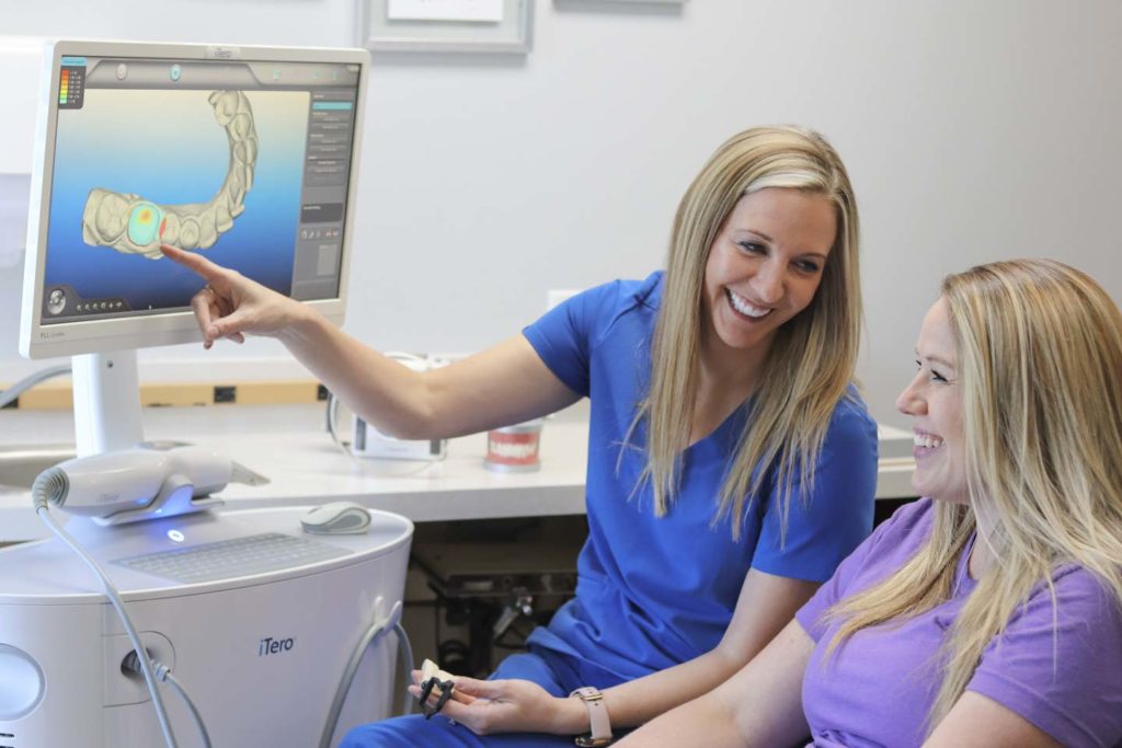 Dr. Ashley Humlicek points to an image on the iTero scanner and speaks to a dental patient