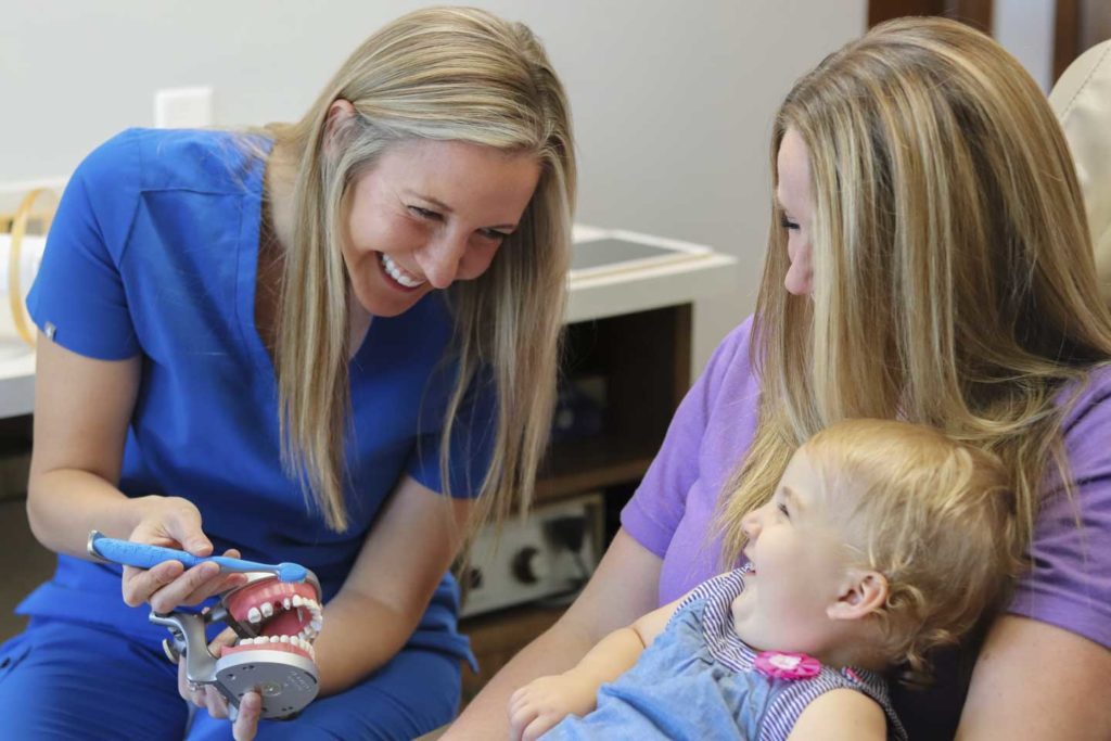 Dr. Ashley Humlicek of Humlicek Family Dental in Wichita, KS showing child how to brush teeth