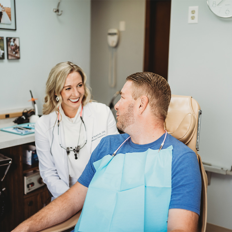Dr. Humlicek smiling at a patient in a dental chair